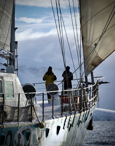 Bow of Infinity Expedition ship sailing in Antarctica, with snow covered mountains in the background.