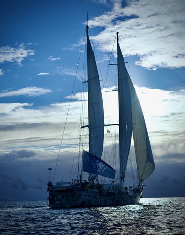 Infinity Expedition sailing ship at sea, flying the Earth Flag.
