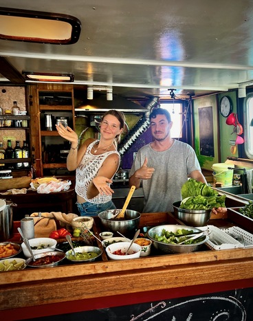 Two Infinity Expedition crew members presenting food on the galley counter.
